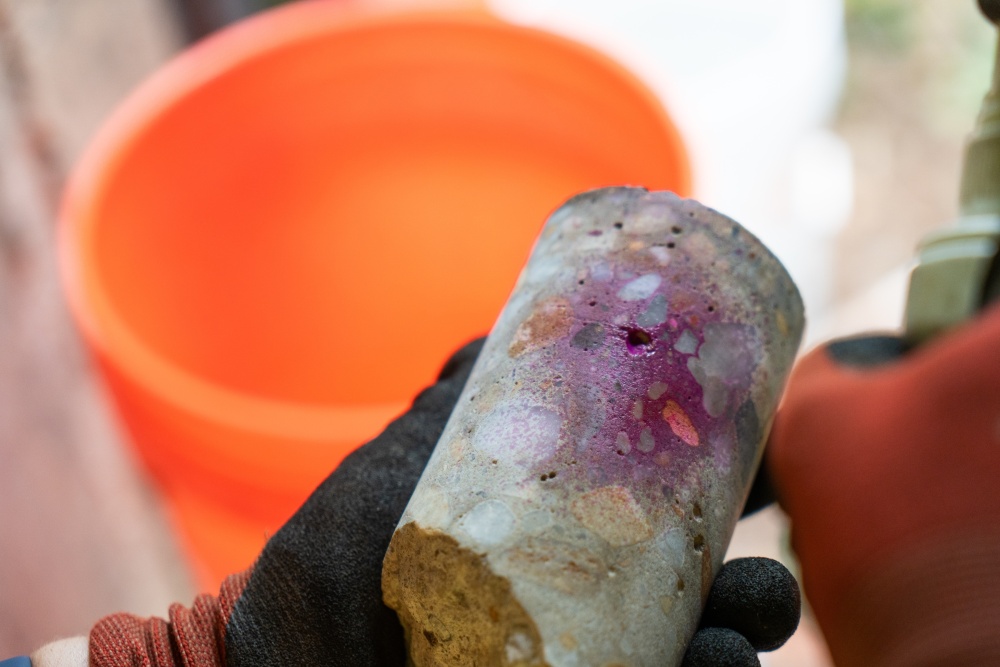 Engineer performs a carbonation depth test, spraying a indicator solution on concrete core. The solution is turning the core pink/purple. which indicates no chlorides.